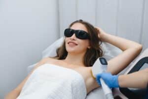 hair removal procedure, young beautiful caucasian smiling brunette woman lying on couch in beauty salon