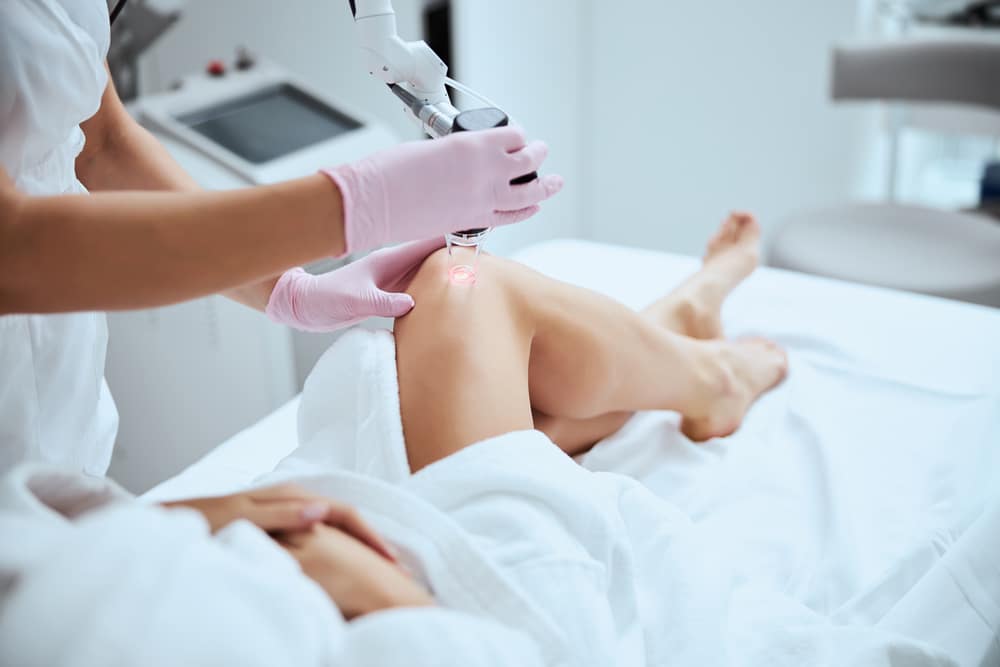 Woman in bathrobe receives laser spider vein treatment
