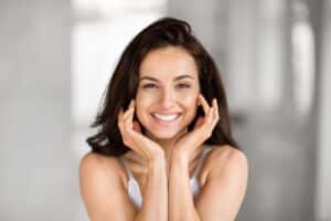 Beautiful brunette woman smiles brightly, happy with her SkinPen microneedling results.