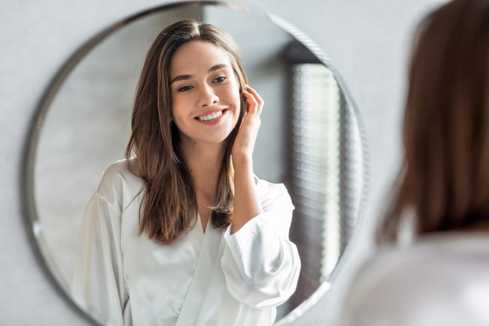 A woman looking in the mirror at the results of laser pigment removal