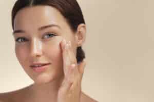 Woman grins in delight, touching her soft skin after a Golden Duo treatment